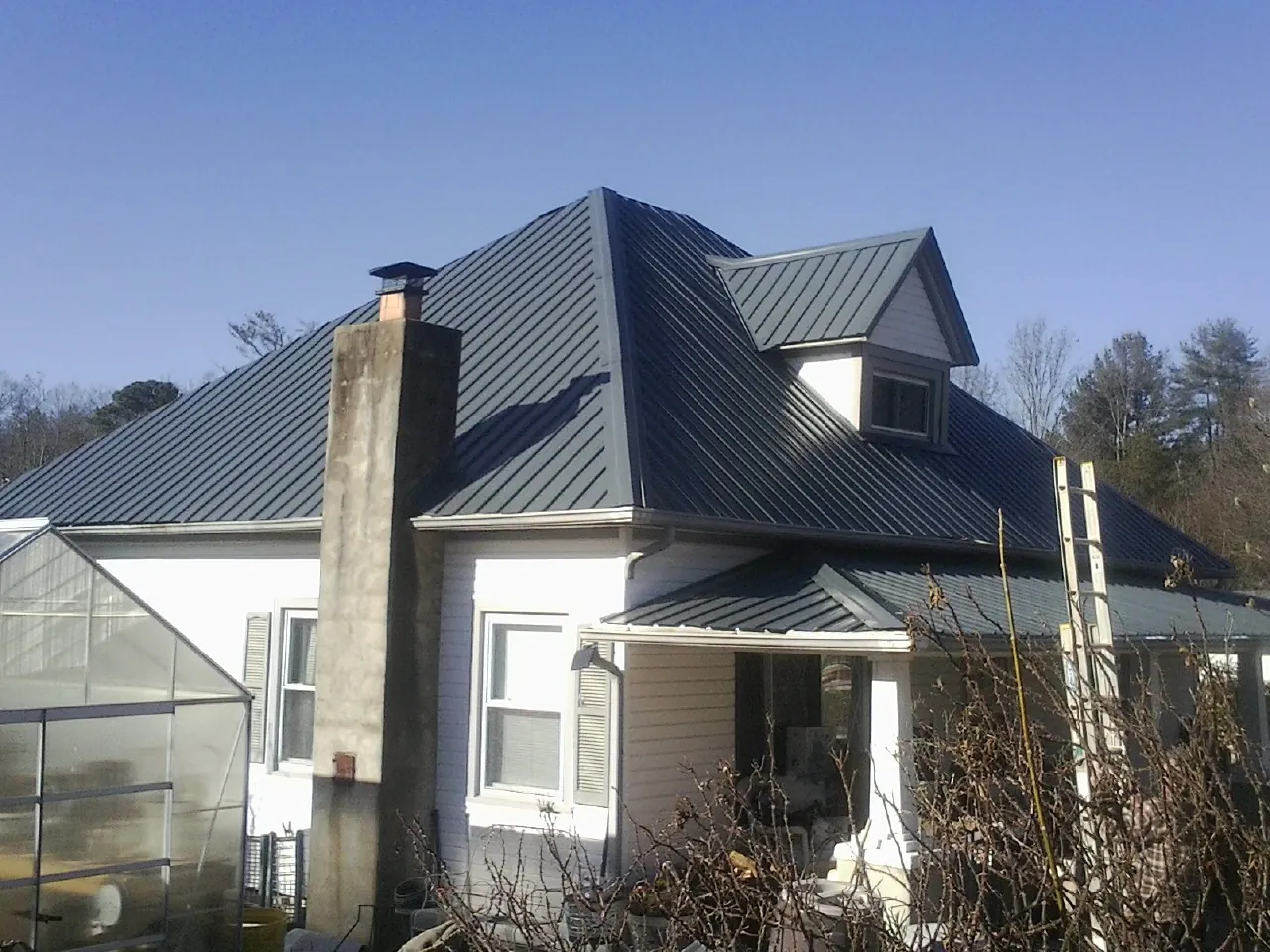Dark blue standing seam metal roof on a white farmhouse with dormer — Slate & Tile Roof Repair by Roofing Brothers in Mount Holly