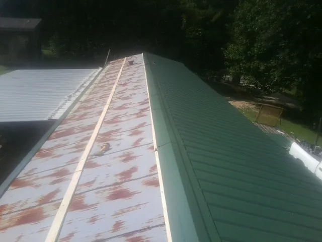 Old rusted panels beside newly installed green metal roofing — Wind Damage Roof Repair by Roofing Brothers in Mount Holly