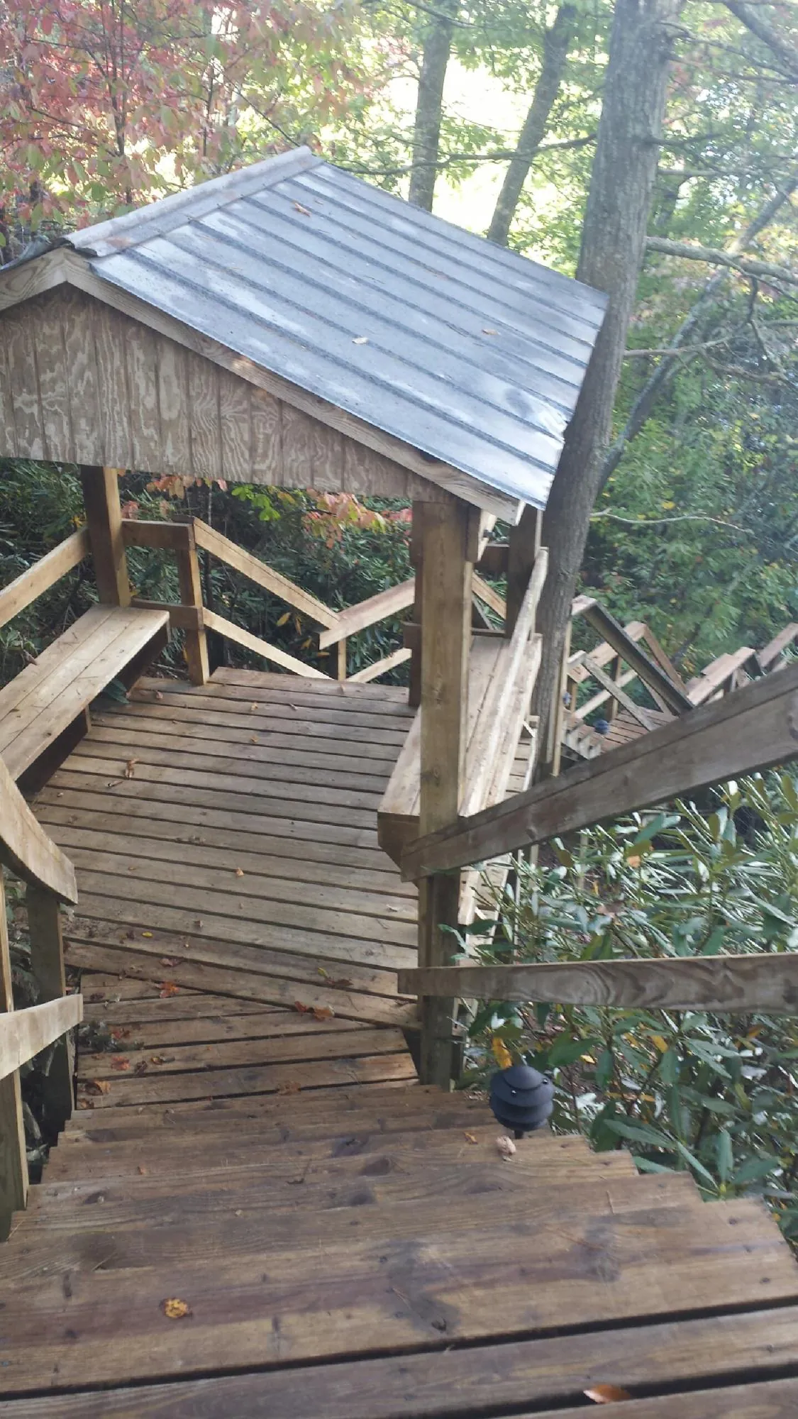 Metal roofed shelter over wooden steps on a wooded walkway — Skylight Repair & Installation work by our crew in Mount Holly