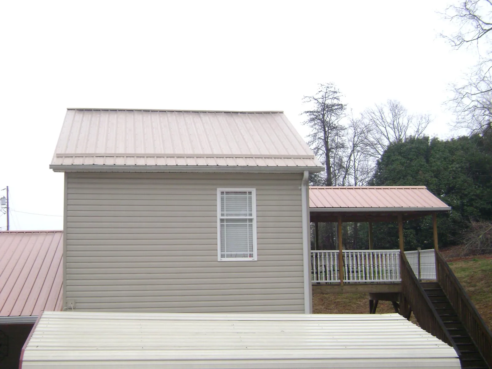 Tan metal roofs on a two story addition and attached porch, from a Roof Replacement job in Mount Holly