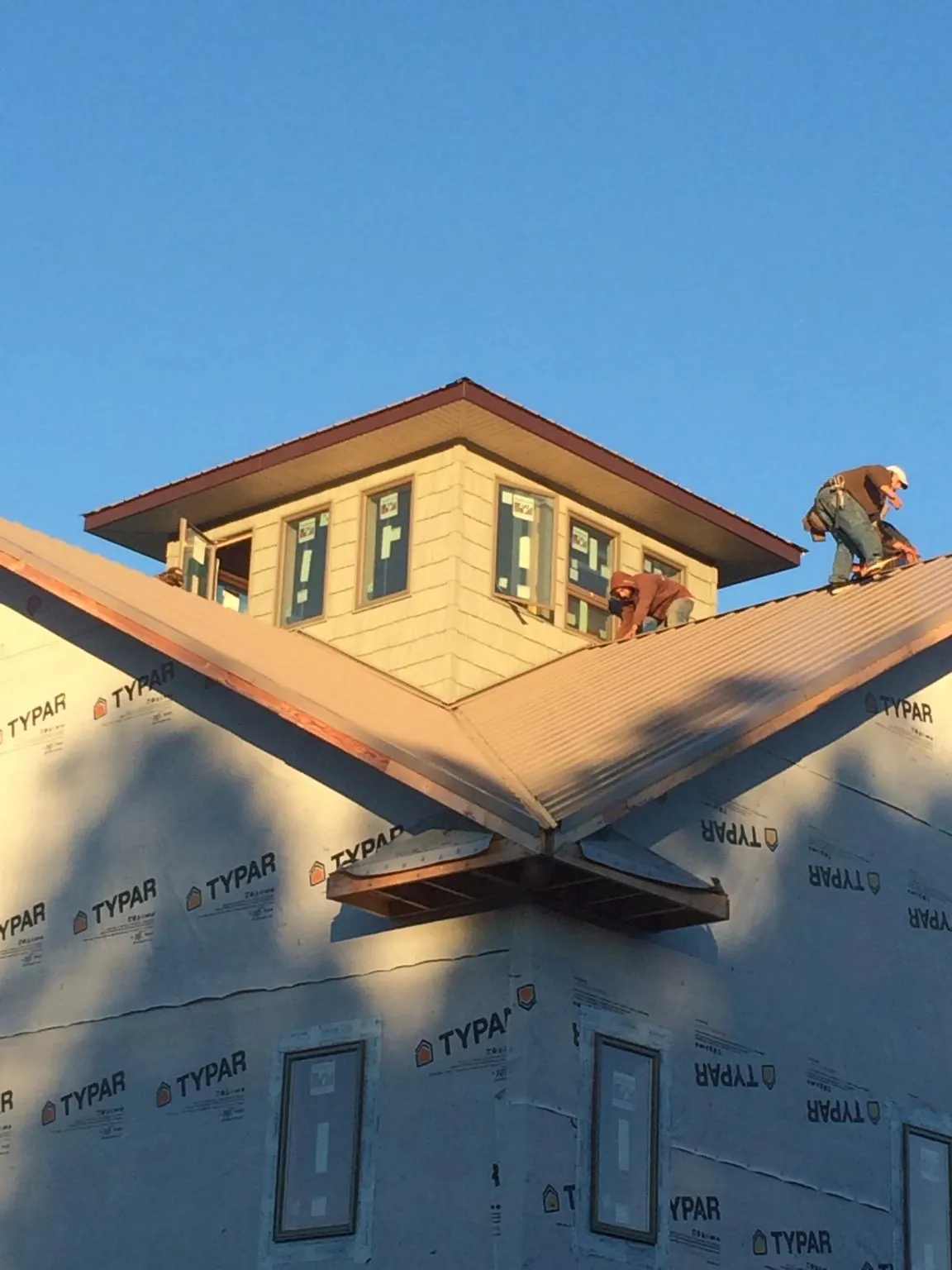 Roofers working around a rooftop cupola on a new metal roof at sunset — Roof Waterproofing in Mount Holly by Roofing Brothers